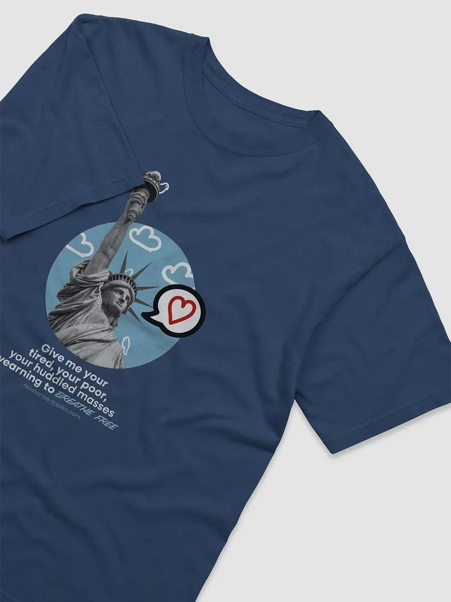 T-shirt design showing an illustration of the Statue of Liberty with a modern graphic design twist. The background features a blue circle with white cartoon-style clouds and small birds. A speech bubble with a red heart inside is placed near the statue. Below, a quote from Emma Lazarus's poem reads: 'Give me your tired, your poor, your huddled masses yearning to breathe free,' with 'breathe free' italicized in a handwritten-style font. The website 'resistance-toolkit.com' is displayed at the bottom.