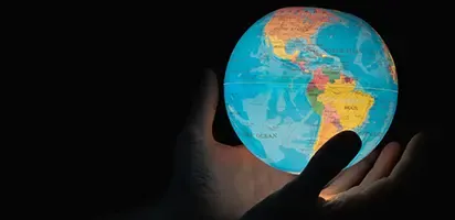 A pair of hands holding an illuminated globe.