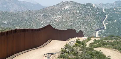 Metal wall extending from the bottom left of the image to the top right. It is creating a scare in the dessert landscape.