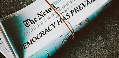 Bound up newspaper with the headline "Democracy Prevails" laying on the ground.