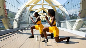 Two women doing lunges on a foot bridge.