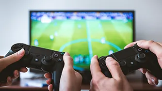 Two video game controllers being held up in front of a TV with a soccer game on.