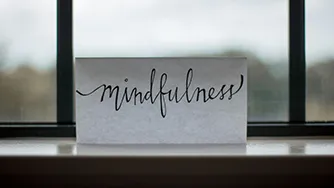 A sheet of paper propped up against a window with the words 'Mindfulness' written on it.